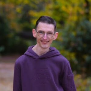 Foto van kandidaat Paul van der Kolk-Kruithof. Op de achtergrond een pad en veel bomen en groen. Foto gemaakt in Asserbos.